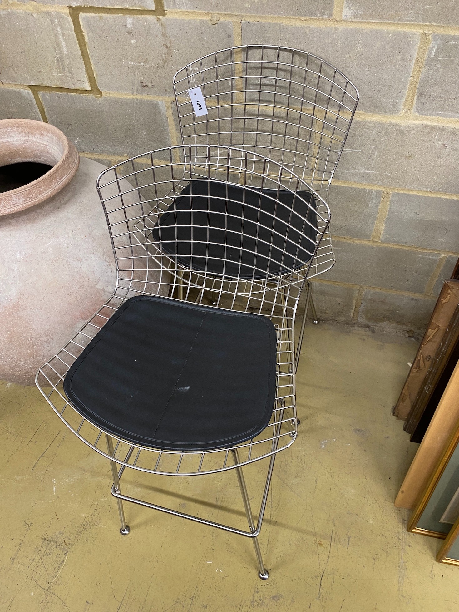 A pair of Harry Bertoia style chrome wired bar chairs with black leather seat pads, width 75cm, height 111cm